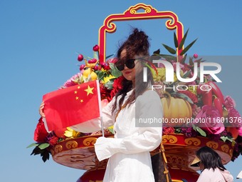 Tourists pose for a group photo in front of the flower beds at Tian 'anmen Square to celebrate the upcoming National Day in Beijing, China,...