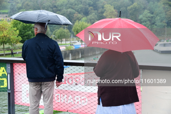 Several people with umbrellas cheer on the Lyon Kayak race on the Saone River in Lyon, France, on September 22, 2024. 