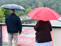 Several people with umbrellas cheer on the Lyon Kayak race on the Saone River in Lyon, France, on September 22, 2024. (