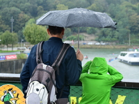 Several people with umbrellas cheer on the Lyon Kayak race on the Saone River in Lyon, France, on September 22, 2024. (