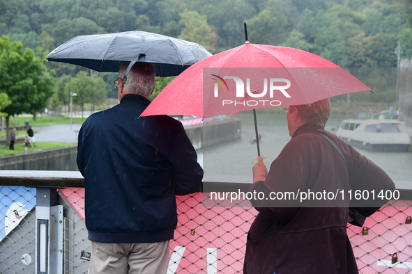 Several people with umbrellas cheer on the Lyon Kayak race on the Saone River in Lyon, France, on September 22, 2024. 