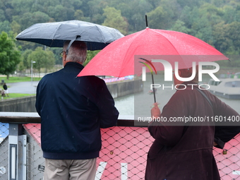 Several people with umbrellas cheer on the Lyon Kayak race on the Saone River in Lyon, France, on September 22, 2024. (