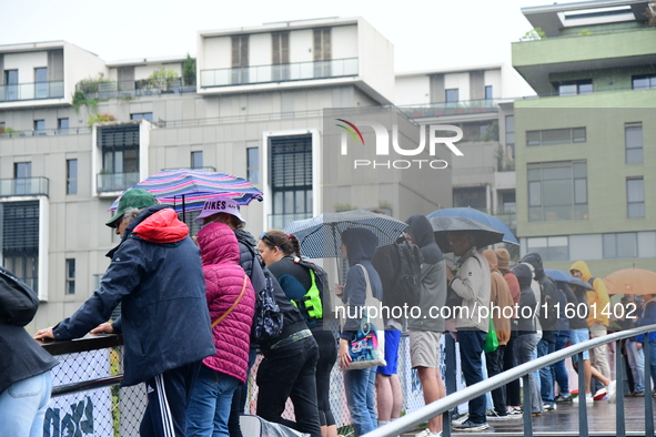 Several people with umbrellas cheer on the Lyon Kayak race on the Saone River in Lyon, France, on September 22, 2024. 