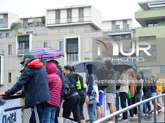 Several people with umbrellas cheer on the Lyon Kayak race on the Saone River in Lyon, France, on September 22, 2024. (