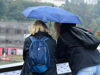 Several people with umbrellas cheer on the Lyon Kayak race on the Saone River in Lyon, France, on September 22, 2024. (