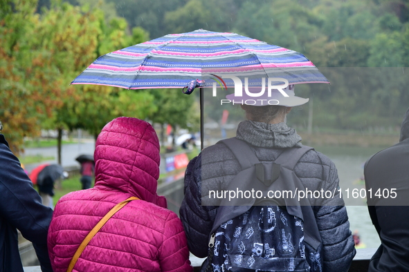 Several people with umbrellas cheer on the Lyon Kayak race on the Saone River in Lyon, France, on September 22, 2024. 