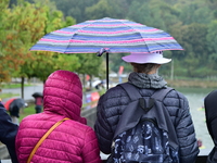 Several people with umbrellas cheer on the Lyon Kayak race on the Saone River in Lyon, France, on September 22, 2024. (