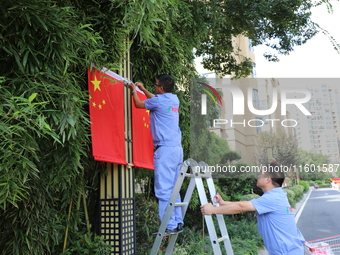 Workers hang national flags to welcome the upcoming National Day in Yancheng, China, on September 23, 2024. (