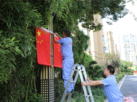 Workers hang national flags to welcome the upcoming National Day in Yancheng, China, on September 23, 2024. (