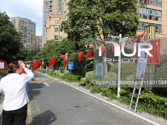 Workers hang national flags to welcome the upcoming National Day in Yancheng, China, on September 23, 2024. (