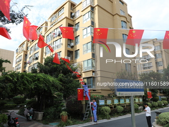 Workers hang national flags to welcome the upcoming National Day in Yancheng, China, on September 23, 2024. (