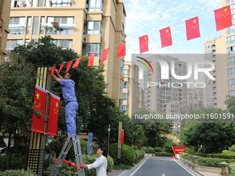 Workers hang national flags to welcome the upcoming National Day in Yancheng, China, on September 23, 2024. (