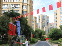 Workers hang national flags to welcome the upcoming National Day in Yancheng, China, on September 23, 2024. (