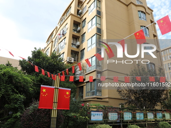 Workers hang national flags to welcome the upcoming National Day in Yancheng, China, on September 23, 2024. (