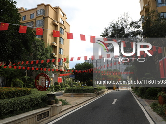 Workers hang national flags to welcome the upcoming National Day in Yancheng, China, on September 23, 2024. (