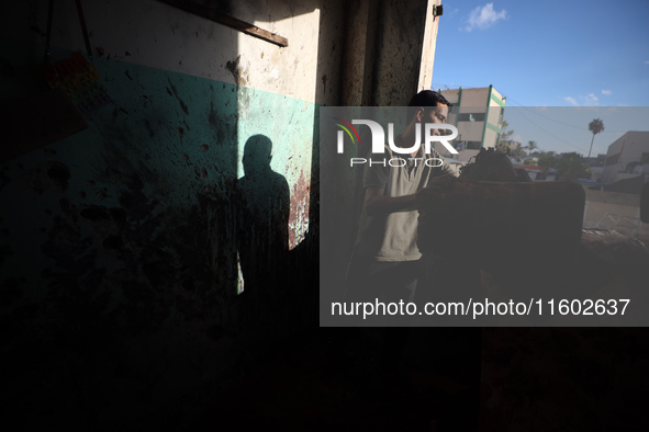 A Palestinian man inspects the damage in a room of a school sheltering displaced people after it is hit by an Israeli airstrike in the Nusei...