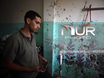 A Palestinian man inspects the damage in a room of a school sheltering displaced people after it is hit by an Israeli airstrike in the Nusei...