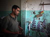 A Palestinian man inspects the damage in a room of a school sheltering displaced people after it is hit by an Israeli airstrike in the Nusei...