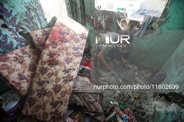 A Palestinian man inspects the damage in a room of a school sheltering displaced people after it is hit by an Israeli airstrike in the Nusei...