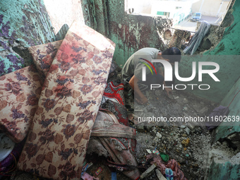 A Palestinian man inspects the damage in a room of a school sheltering displaced people after it is hit by an Israeli airstrike in the Nusei...