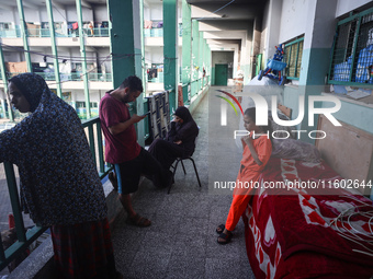 Palestinians stand at a school sheltering displaced people after an Israeli air strike hits the site in Nuseirat, Gaza Strip, on September 2...