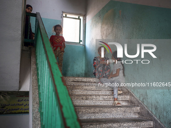 Palestinians stand at a school sheltering displaced people after an Israeli air strike hits the site in Nuseirat, Gaza Strip, on September 2...