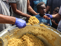 Palestinians receive cooked food rations as part of a volunteer initiative in a makeshift displacement camp in Deir Al-Balah, Gaza Strip, on...