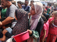 Palestinians receive cooked food rations as part of a volunteer initiative in a makeshift displacement camp in Deir Al-Balah, Gaza Strip, on...