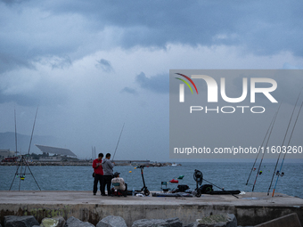 Fishermen and some passers-by are surprised by the unstable autumn weather on the Barcelona coast, in Barcelona, Spain, on September 23, 202...