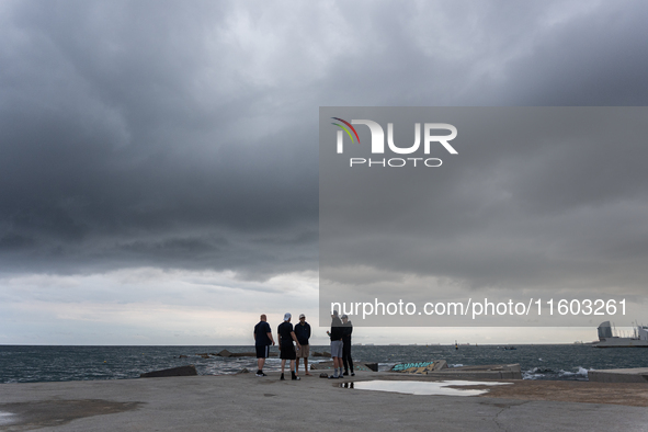 Fishermen and some passers-by are surprised by the unstable autumn weather on the Barcelona coast, in Barcelona, Spain, on September 23, 202...