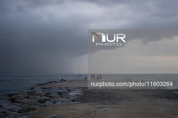 Fishermen and some passers-by are surprised by the unstable autumn weather on the Barcelona coast, in Barcelona, Spain, on September 23, 202...