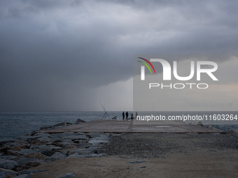 Fishermen and some passers-by are surprised by the unstable autumn weather on the Barcelona coast, in Barcelona, Spain, on September 23, 202...