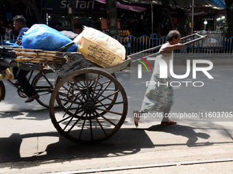 A laborer pulls a hand-pulled rickshaw loaded with consumer goods on a road at a wholesale market in Kolkata, India, on September 21, 2024....