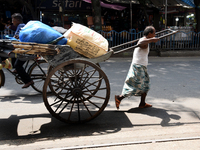 A laborer pulls a hand-pulled rickshaw loaded with consumer goods on a road at a wholesale market in Kolkata, India, on September 21, 2024....