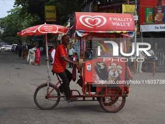 An ice cream salesman cycles on an ice cream cart across the street in Kolkata, India, on September 21, 2024. (