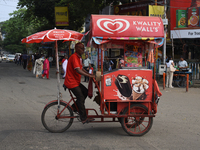 An ice cream salesman cycles on an ice cream cart across the street in Kolkata, India, on September 21, 2024. (