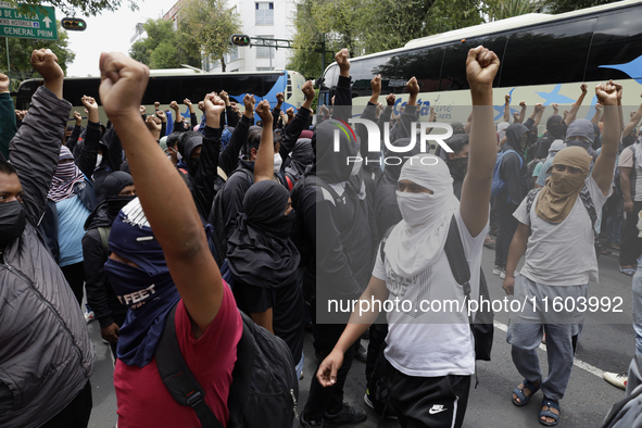 Colleagues of the 43 missing students from Ayotzinapa protest with fists raised outside the Ministry of the Interior in Mexico City, Mexico,...