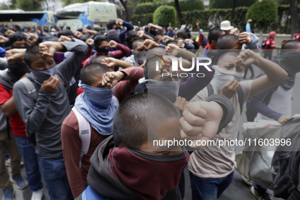 Colleagues of the 43 missing students from Ayotzinapa protest with fists raised outside the Ministry of the Interior in Mexico City, Mexico,...