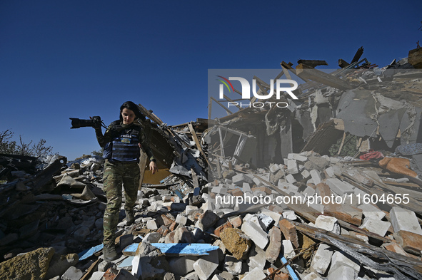 A photojournalist with a camera stands on the ruins of a house destroyed by Russian shelling in the Vozdvyzhivka territorial community, Zapo...