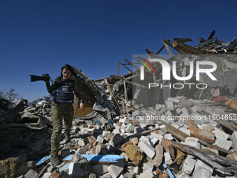 A photojournalist with a camera stands on the ruins of a house destroyed by Russian shelling in the Vozdvyzhivka territorial community, Zapo...