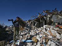 A photojournalist with a camera stands on the ruins of a house destroyed by Russian shelling in the Vozdvyzhivka territorial community, Zapo...