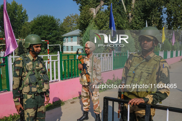 Indian security personnel stand guard as polling officials carry electronic voting machines (EVM) at a distribution center on the eve of the...