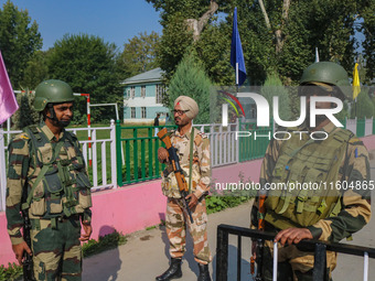 Indian security personnel stand guard as polling officials carry electronic voting machines (EVM) at a distribution center on the eve of the...