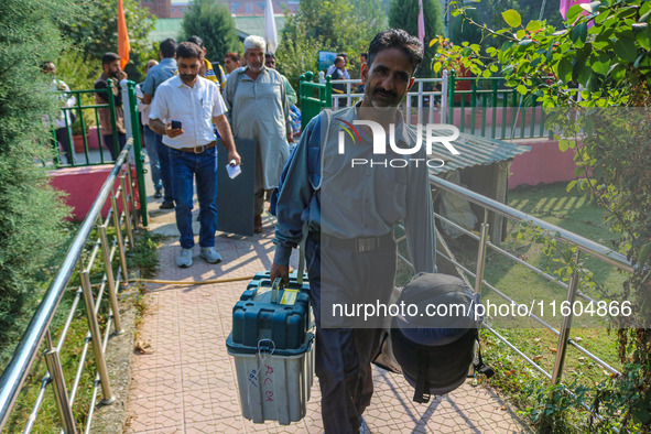 Polling officials carry electronic voting machines (EVM) at a distribution center in Srinagar, Jammu and Kashmir, on September 24, 2024, on...