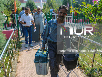 Polling officials carry electronic voting machines (EVM) at a distribution center in Srinagar, Jammu and Kashmir, on September 24, 2024, on...