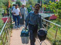 Polling officials carry electronic voting machines (EVM) at a distribution center in Srinagar, Jammu and Kashmir, on September 24, 2024, on...