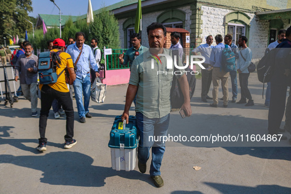 Polling officials carry electronic voting machines (EVM) at a distribution center in Srinagar, Jammu and Kashmir, on September 24, 2024, on...