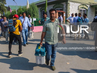 Polling officials carry electronic voting machines (EVM) at a distribution center in Srinagar, Jammu and Kashmir, on September 24, 2024, on...