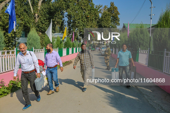 Polling officials carry electronic voting machines (EVM) at a distribution center in Srinagar, Jammu and Kashmir, on September 24, 2024, on...