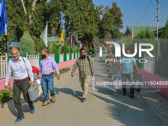 Polling officials carry electronic voting machines (EVM) at a distribution center in Srinagar, Jammu and Kashmir, on September 24, 2024, on...